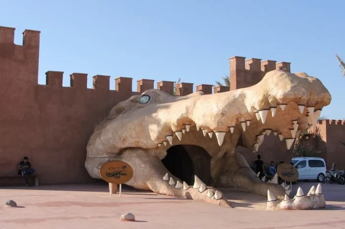 Large stone crocodile head sculpture at the entrance of Crocopark.